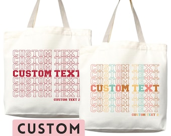 Op de afbeelding: Twee off-white canvas draagtassen met elk twee schouderbanden. De linker tas heeft rode tekst met CUSTOM TEXT in een herhalend raster en CUSTOM TEXT 2 onderaan. De rechter tas toont dezelfde tekst in een meerkleurig verloop.