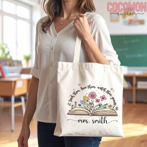 Pu&ograve; includere: Borsa tote color crema con design floreale e libro aperto. Il testo recita "teach them, love them, watch them grow" e "mrs. smith". La borsa ha manici lunghi.