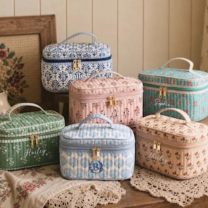 May include: Six rectangular quilted cosmetic bags with top handles and gold zippers. The bags feature various floral and shell patterns in blue, pink, green, and peach colors. Each bag is personalized with embroidered names or initials like Hailey, Shannon, Sophie, and Shirley.