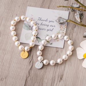 a white flower and two bracelets on a table