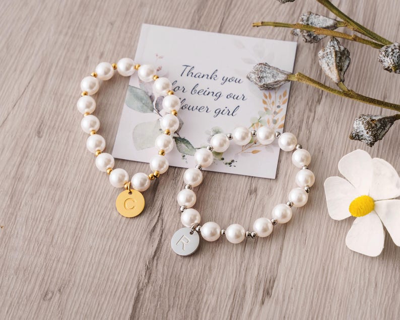 a white flower and two bracelets on a table