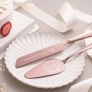 a pink cake knife and a cake server on a white plate, with a strawberry slice on the cake.