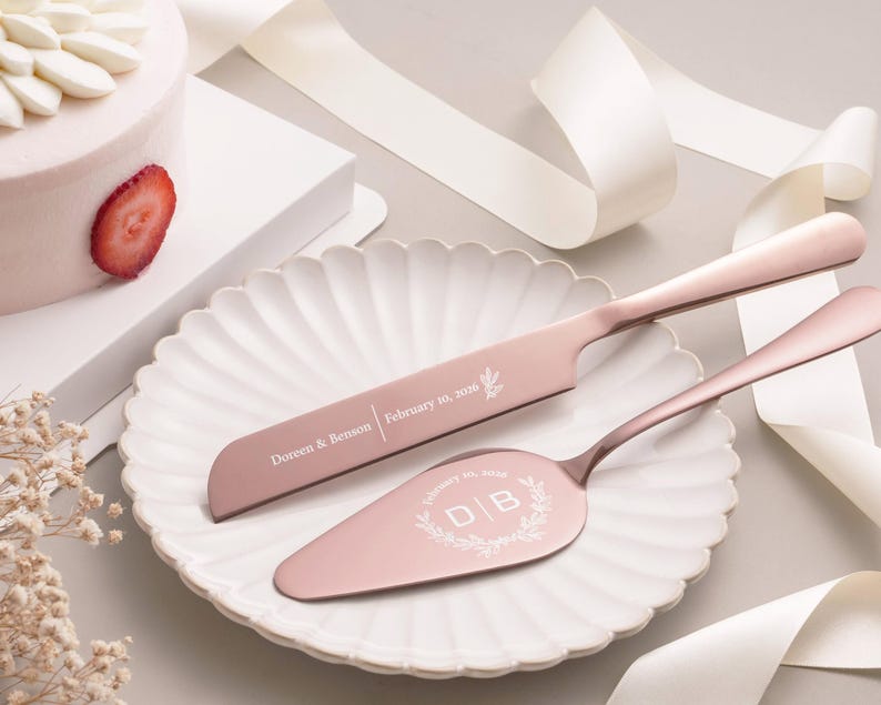 a pink cake knife and a cake server on a white plate, with a strawberry slice on the cake.