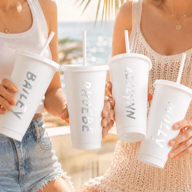 Two women holding white cups with personalized names on them.