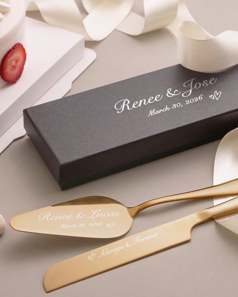 a wedding cake, a black box, and two gold cake servers with the names 'Renee & Jose' engraved on them.