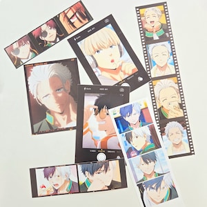 May include: A collection of photo booth strips featuring anime characters with white and green accents. The strips are printed on white paper with black borders and have a film strip design. The characters are smiling and posing for the camera.