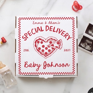 May include: A white pizza box with red text and a heart-shaped pizza design. The text reads "Emma & Adam's Special Delivery" and "Baby Johnson". A baby bottle, pacifier, and sonogram images are also present.