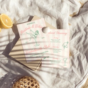 May include: Pink and green invitation for a bachelorette party in Palm Springs, California. The invitation features a martini glass with a woman in a bikini sitting on the rim. The text reads "Amanda's Martinis & Bikinis Bachelorette Club Palm Springs, California May 9th - 12th 2024".