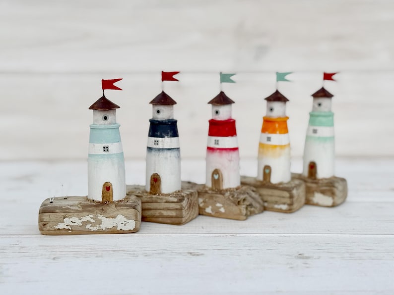 Pu&ograve; includere: Cinque figurine di fari in legno in miniatura con colori diversi: azzurro, blu navy, rosso, arancione e verde menta. Ogni faro ha un tetto marrone e una piccola bandiera. Montati su basi di legno invecchiato.