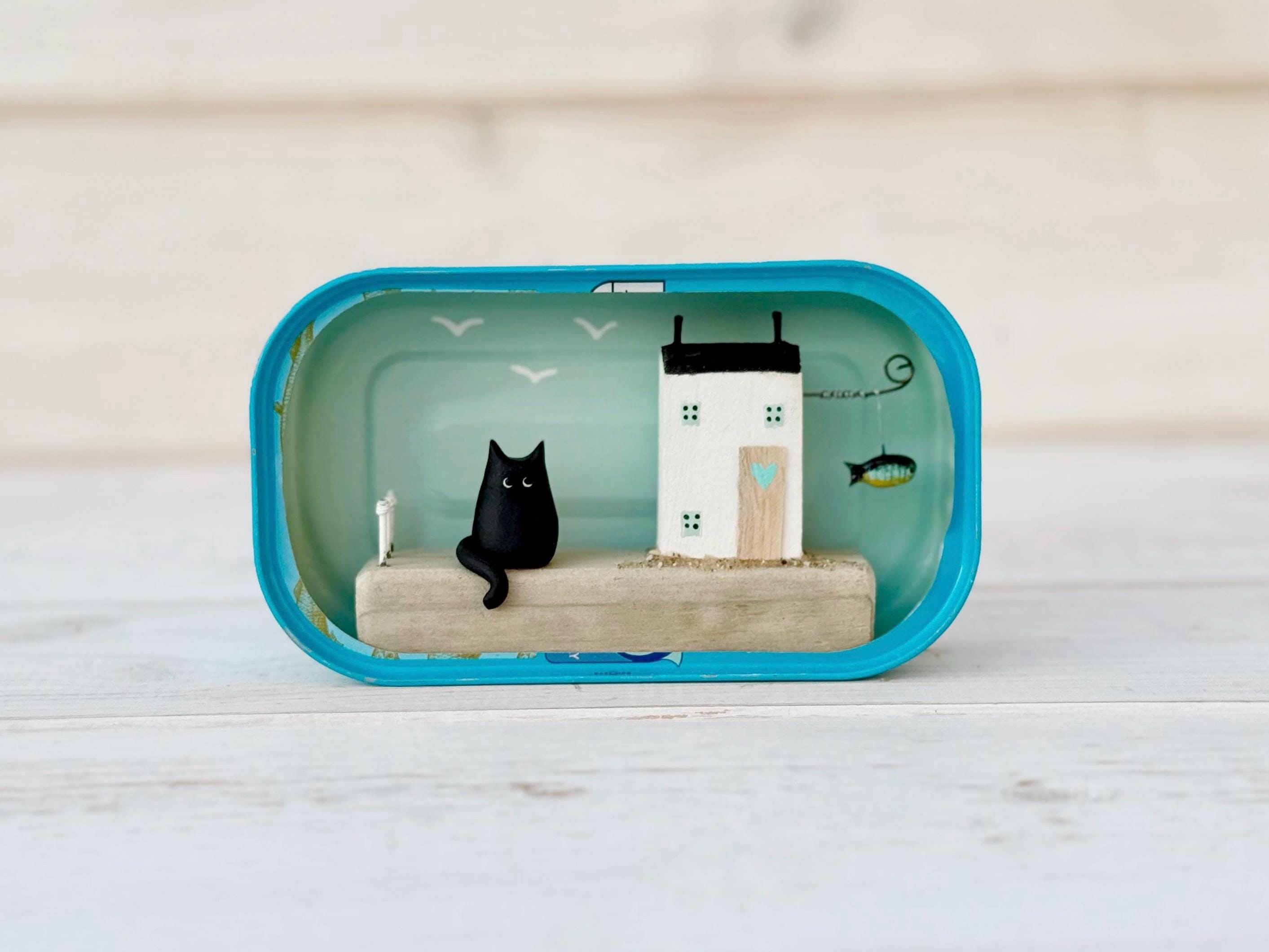 Sardine Tin Cat Cottage. Scena di tronchi galleggianti.