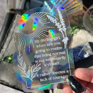 May include: A holographic sticker with a white floral design and the text "My darling girl, when are you going to realize that being normal is not necessarily a virtue? It rather denotes a lack of courage!"