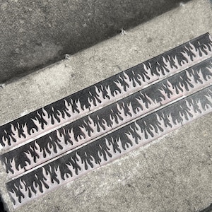 May include: Open journal with gray pages and three strips of decorative tape featuring a black flame design. A roll of black patterned tape sits nearby. The box in the background reads "Arch Michael".