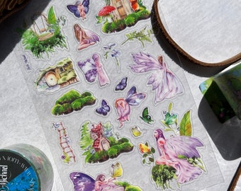 May include: A sheet of clear sticker paper with various fairy and mushroom illustrations. The stickers feature a whimsical fairy garden theme with purple, pink, and green colors.
