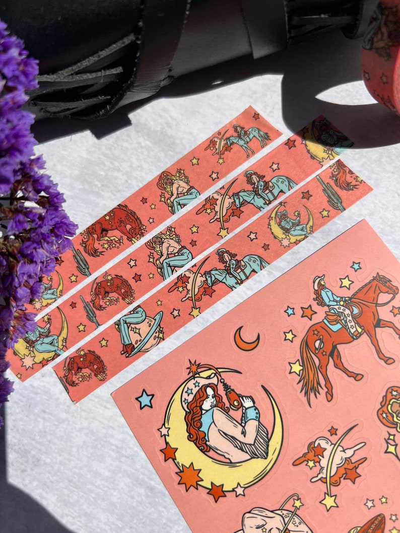 K&ouml;nnte beinhalten: Drei Rollen rosa Washi-Tape mit einem sich wiederholenden Muster einer Frau, die ein Pferd reitet, einem Halbmond und Sternen. Das Klebeband befindet sich auf einer wei&szlig;en Oberfl&auml;che.