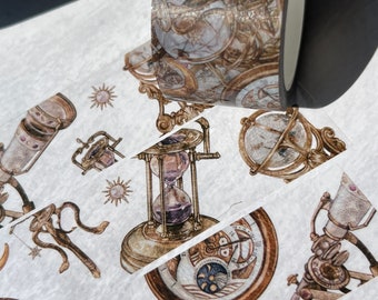 May include: A roll of decorative washi tape featuring a vintage celestial theme. The tape displays illustrations of globes, hourglasses, telescopes, and suns in shades of brown, gold, and white. The tape is on a white background.