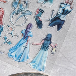 May include: A sheet of fantasy-themed stickers featuring illustrations of dragons, women in flowing gowns, a knight, and other mystical elements. The stickers are in shades of blue, purple, and white, with a transparent border.