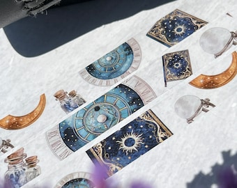 May include: Assortment of washi tape featuring celestial and mystical designs. The tape includes a moon, stars, a sun, a clock face, a book, and a bottle with a cork. The tape is on a white background.