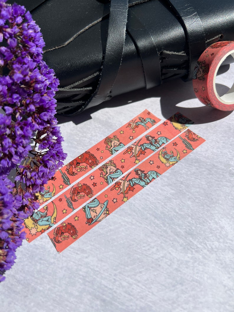 K&ouml;nnte beinhalten: Drei Rollen rosa Washi-Tape mit einem sich wiederholenden Muster einer Frau, die ein Pferd mit Sternen und einer Mondsichel reitet.