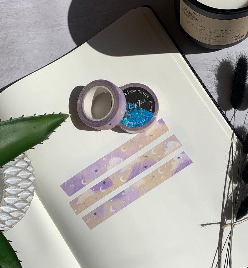 May include: Three rolls of washi tape with a purple, pink, and beige background. The tape features a moon, stars, and clouds design. The tape is labeled "Washi Tape - 15mm x 5m - Mini"