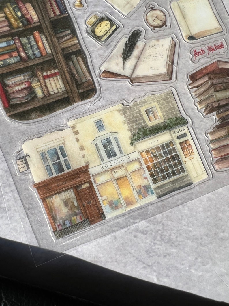 May include: A watercolor illustration of a bookstore with two storefronts. The storefront on the left says "The Book Shop" and the storefront on the right says "Bookshop No. 75".
