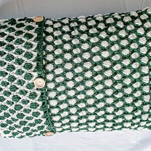May include: A green and white crocheted pillow with a textured pattern and three wooden buttons.