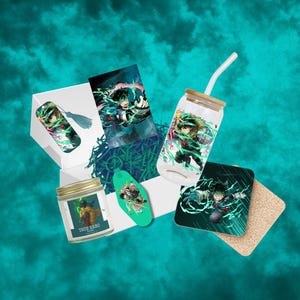 May include: A selection of anime-themed merchandise, including a glass tumbler with a straw, a coaster, a bookmark, a keychain, and a candle. The items are teal and green, and are arranged in a white box. The candle has the text "TRUE HERO".