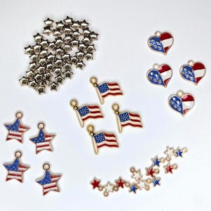May include: A collection of patriotic charms and embellishments. Includes gold-toned star-shaped studs, American flag charms, star-shaped charms with red, white, and blue enamel, and heart-shaped charms with flag designs. Ideal for jewelry making or craft projects.