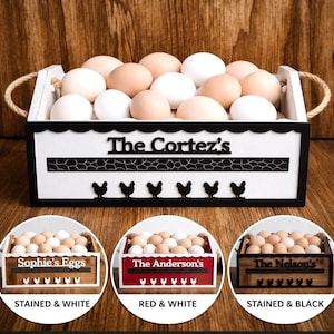 May include: A white wooden egg crate with the text "The Cortez's" and a row of black chicken silhouettes. The crate is filled with brown and white eggs. Additional crates are shown with different names and colour schemes.