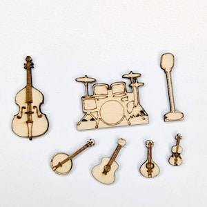 May include: A collection of wooden musical instrument cutouts, including a double bass, drum set, microphone, banjo, two guitars, and a violin. The instruments are light brown with etched details, perfect for crafting or scrapbooking projects.