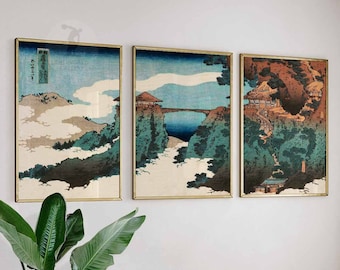 May include: Three framed prints of Japanese woodblock prints depicting a mountain landscape with a bridge and a village. The prints are in shades of blue, green, brown, and white.