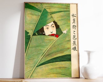 May include: A framed Japanese woodblock print featuring a woman peeking through large green leaves. The artwork has a traditional style with Japanese text on the right side. The print is displayed on a wooden shelf with a white vase.