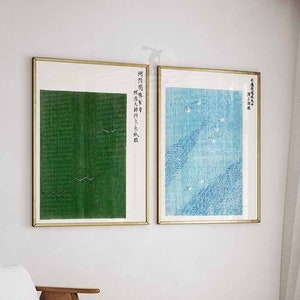 May include: Two framed prints with Japanese text and abstract designs. The print on the left is green with white birds. The print on the right is blue with white birds.