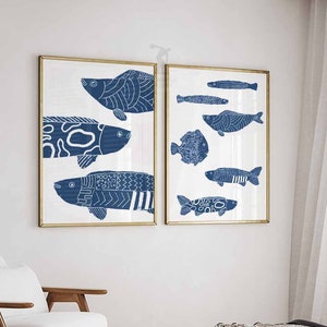 Peut inclure: Deux impressions encadrées d'illustrations stylisées de poissons bleus et blancs. Les impressions sont accrochées à un mur blanc dans une chambre à coucher.