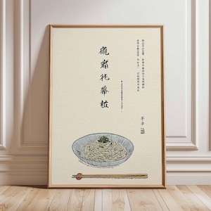 May include: A framed art print featuring a detailed illustration of a bowl of noodles with chopsticks. The artwork is in a minimalist style with Japanese text and a beige background. The frame is made of wood.