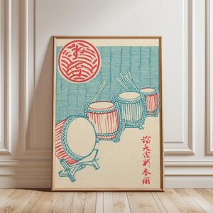 May include: A framed print featuring a Japanese-style illustration of drums. The artwork showcases red and blue drums with drumsticks, set against a light blue backdrop. A red circular design is at the top, and Japanese text is on the right.