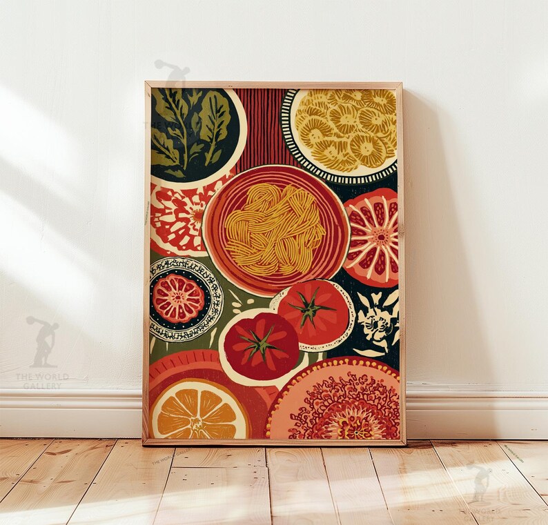 May include: A framed art print featuring a colorful, stylized illustration of food items. The artwork includes plates of pasta, tomatoes, citrus slices, and decorative patterns in shades of red, orange, green, and yellow. The print is displayed on a wooden floor.