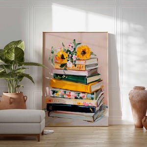 May include: A framed art print featuring a stack of books with colorful spines, topped with sunflowers and other flowers. The artwork is displayed in a room with a potted plant, a footstool, and decorative pottery.