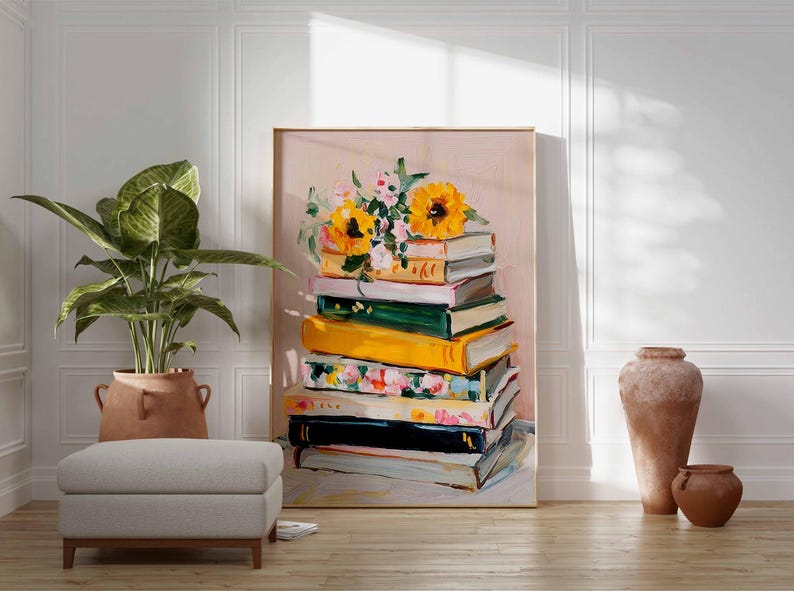 May include: A framed art print featuring a stack of books with colorful spines, topped with sunflowers and other flowers. The artwork is displayed in a room with a potted plant, a footstool, and decorative pottery.