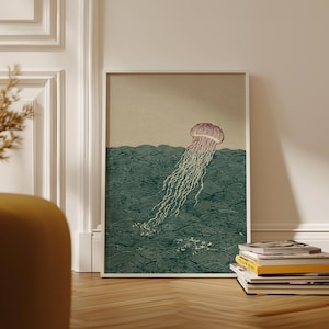 May include: A framed art print featuring a stylized illustration of a jellyfish in the ocean. The jellyfish is depicted with a reddish-brown bell and long, flowing tentacles. The ocean is rendered in shades of green, with wave patterns.