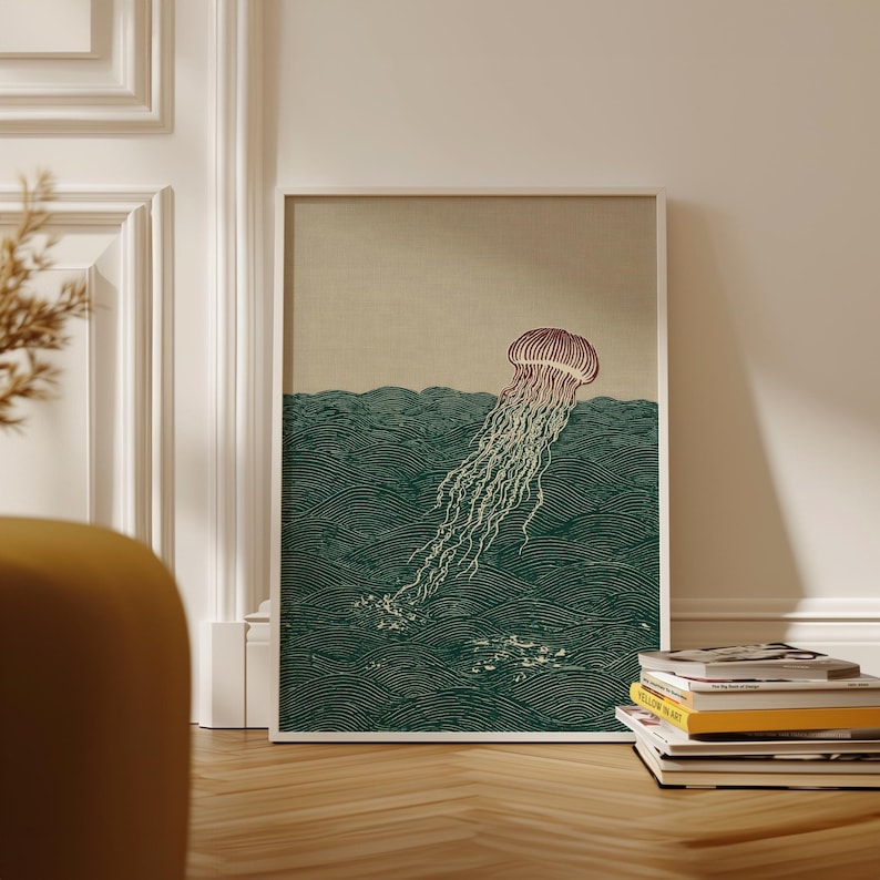 May include: A framed art print featuring a stylized illustration of a jellyfish in the ocean. The jellyfish is depicted with a reddish-brown bell and long, flowing tentacles. The ocean is rendered in shades of green, with wave patterns.