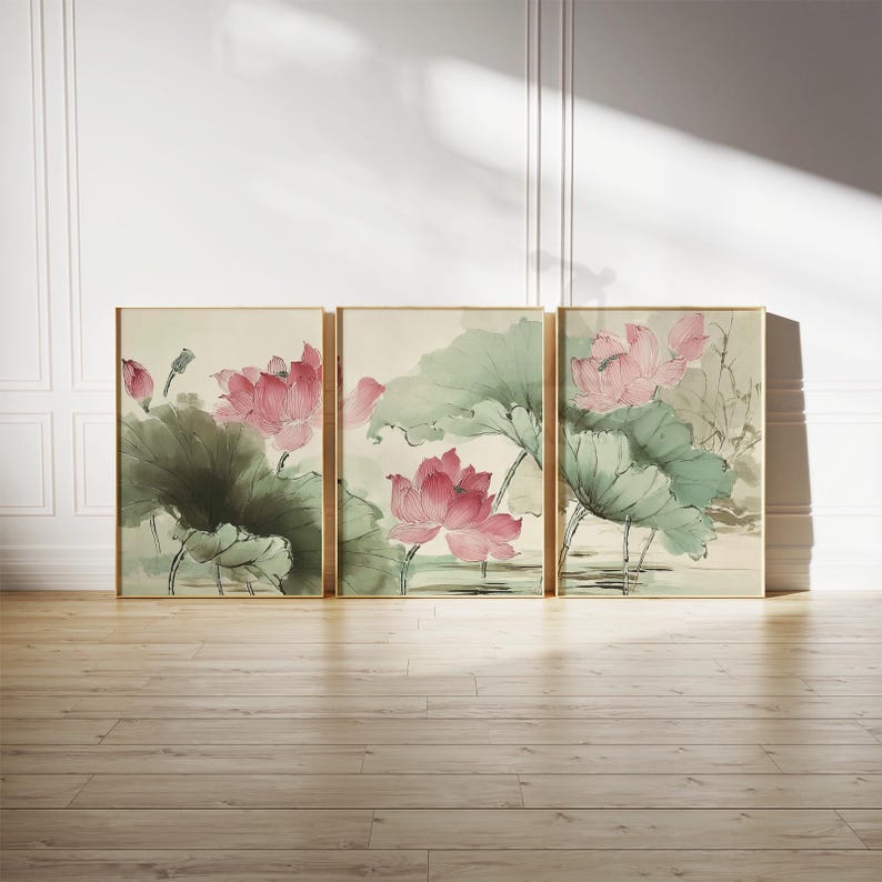 May include: Three framed art prints featuring watercolor paintings of pink lotus flowers and large green leaves. The artwork has a traditional Asian style, with gold frames and a neutral background. The prints are displayed on a wooden floor.