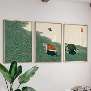 May include: Three framed art prints with gold frames, each depicting sea turtles. The artwork shows turtles swimming in green water against a cream background. One turtle has an orange shell, and another has a green shell.