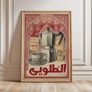 May include: Framed vintage-style coffee advertisement. The artwork features a silver stovetop espresso maker, a cup and saucer, and two bags of coffee. The background is a deep red with ornate patterns, and the text is in Arabic.