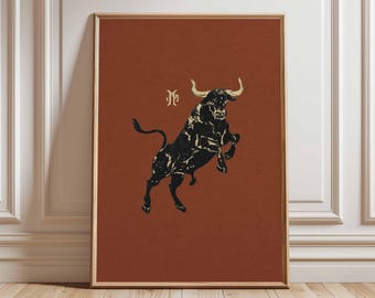 May include: Framed art print featuring a black bull illustration on a rust-colored background. The bull is depicted rearing up, with white horns and a textured appearance. A stylized monogram is above the bull. The artwork is in a wooden frame.