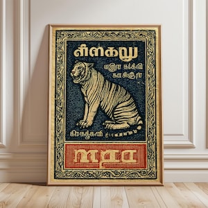 May include: A framed vintage-style poster featuring a seated tiger illustration. The tiger is golden with black stripes, set against a dark blue background. The poster includes text in a foreign language and is framed in a gold-colored border.