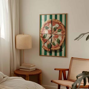 May include: A framed print of a pizza cut into slices, with tomatoes, basil, and mozzarella cheese. The background has green and white vertical stripes. The print is in a wooden frame and hangs on a white wall.