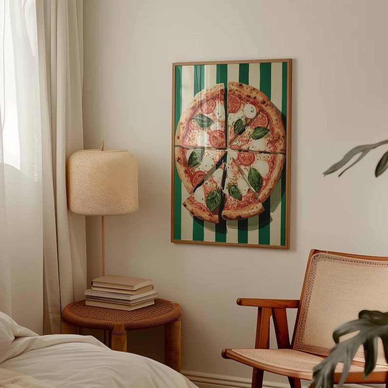 May include: A framed print of a pizza cut into slices, with tomatoes, basil, and mozzarella cheese. The background has green and white vertical stripes. The print is in a wooden frame and hangs on a white wall.