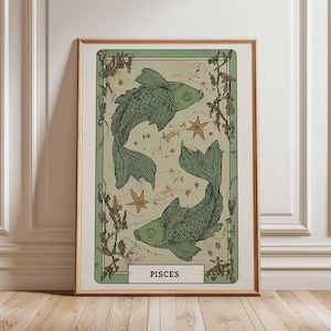 May include: Framed art print featuring two green fish swimming in opposite directions, surrounded by stars and botanical elements. The word "PISCES" is displayed at the bottom. The artwork has a vintage aesthetic with a light green and beige color palette.