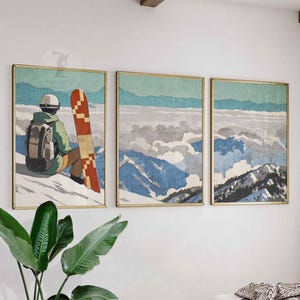 Peut inclure: Ensemble de trois impressions d'art encadrées représentant une scène de montagne hivernale. L'impression de gauche montre une personne avec un snowboard. Les deux autres impressions représentent des chaînes de montagnes avec de la neige et des nuages. Les cadres ont une finition dorée.