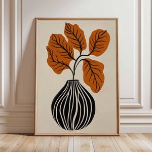 May include: A framed art print depicting a plant with large orange leaves in a black and white striped vase. The artwork has a neutral background and a wooden frame, suitable for home decor.